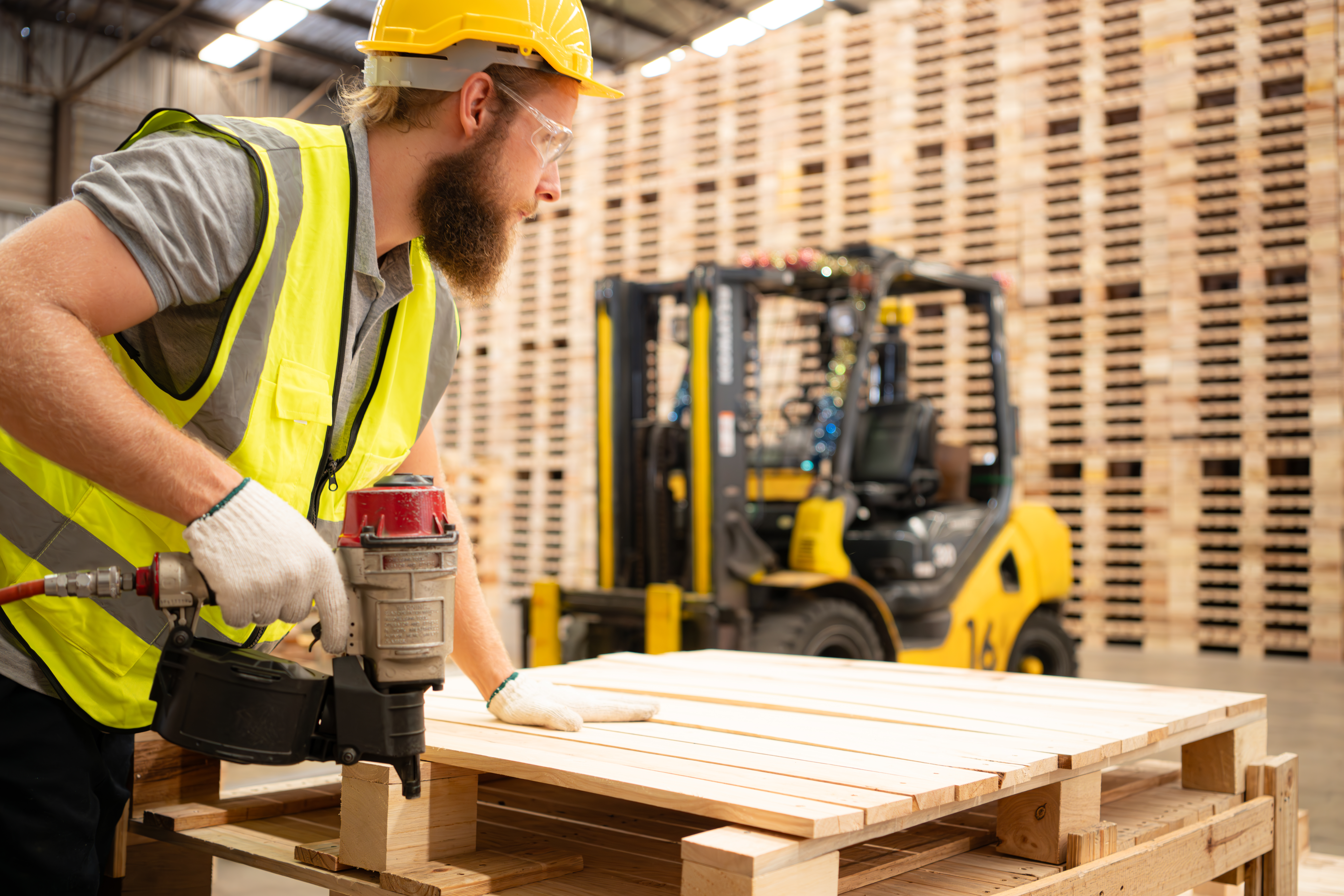 Young workers working in a woodworking factory, Using a nailing machine to assemble wooden pallets